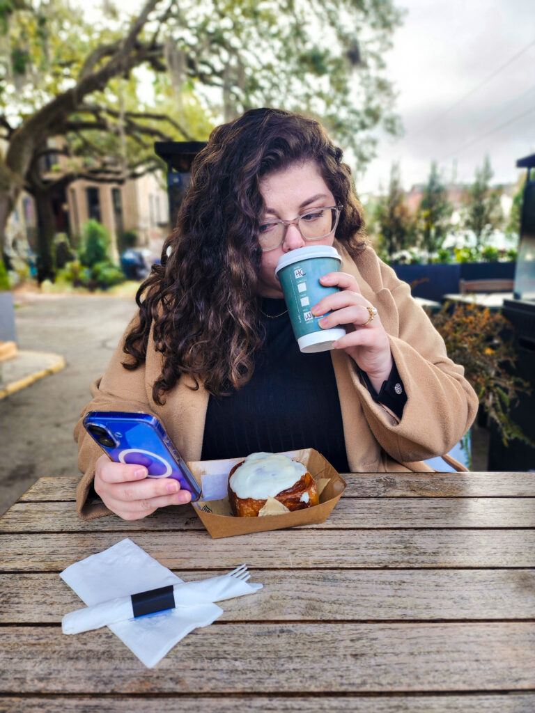 Kathleen drinking coffee and looking at emails on her phone